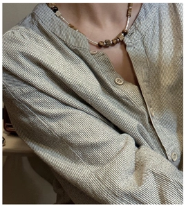 Detail of beaded necklace with tiger eye stones and wooden blocks on striped shirt