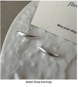 Macro view of matte S925 sterling silver water drop earrings on a white ceramic plate
