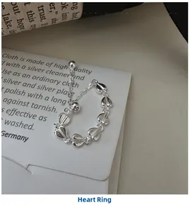 Macro shot of silver heart chain ring with a polished bead pendant on aesthetic backdrop