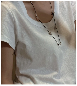Detail of S925 silver knot long necklace with black cord and beads on a model