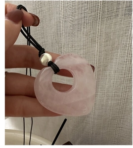 Dettaglio di un ciondolo in quarzo rosa a forma di cuore su un cordino nero
