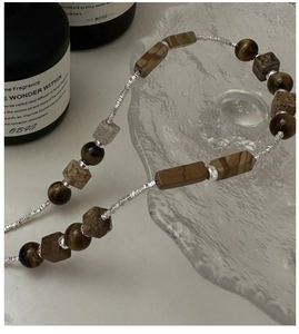 Detailed view of S925 silver beaded necklace with brown tiger eye stone on glass tray