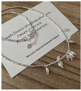 Macro detail of S925 silver necklace featuring delicate freshwater pearl pendants and clasp