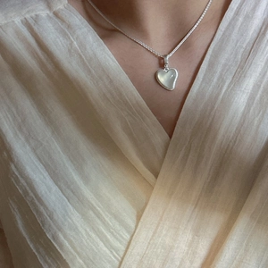 Collier avec pendentif cœur en argent S925 et agate blanche porté par un mannequin femme