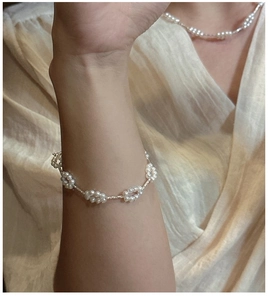 Detail eines gewebten Perlenblumen-Armbands am Handgelenk mit elegantem Hintergrund