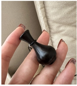 Primo piano di un ciondolo a bottiglia in ebano nero vintage tenuto in mano su una collana