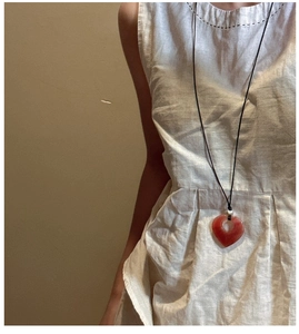 Dettaglio di una collana con ciondolo a cuore in pietra naturale rossa su cordino nero