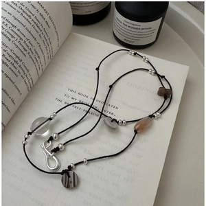 Detail of S925 silver beaded knot necklace on a book with crystal and shell accents