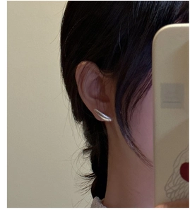 Detail view of S925 sterling silver matte teardrop earrings worn on the earlobe