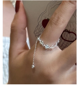 Detailed view of S925 sterling silver chain ring with heart and ball charms on finger