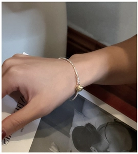 Close-up of minimalist S925 silver bracelet featuring a golden mirror bead on a wrist
