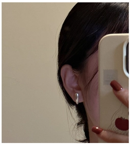 Close-up of a model wearing minimalist silver water drop earrings in a mirror selfie