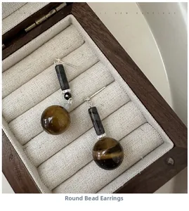 Detailed view of S925 silver earrings with tiger eye and obsidian beads on velvet