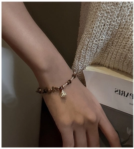 Detail of S925 silver bracelet with tiger eye stones and a shell pendant on a wrist