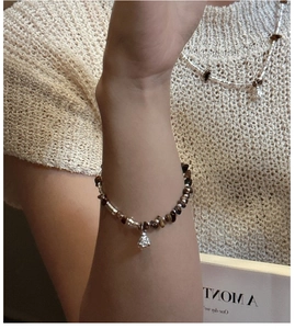 Detail of S925 silver tiger eye bracelet with flower pendant worn by a model