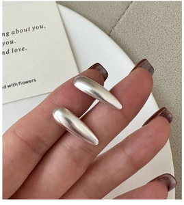 Detail of matte silver teardrop earrings held by fingers showing brushed metal texture