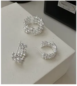 Detail shot of silver braided jewelry set featuring textured ring and hoop earrings