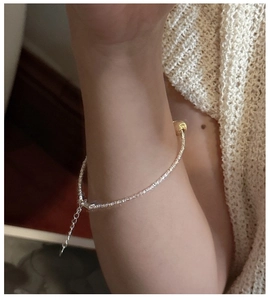 Close-up of S925 sterling silver chain with a gold cat eye bead on model's wrist