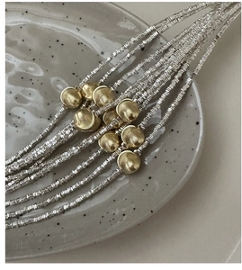 Detail of silver textured beads and golden brushed spheres on a minimalist bracelet
