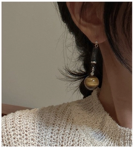 Detail of drop earring with tiger eye bead and geometric retro silver components