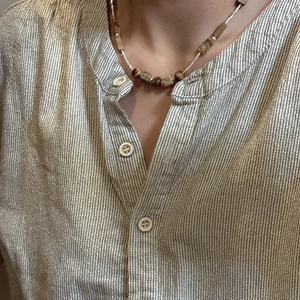 Minimalist S925 silver necklace with brown stone beads on a striped linen shirt