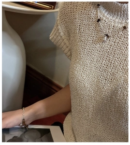 Detail of S925 silver chain bracelet with tiger eye stones on beige openwork knit sleeve