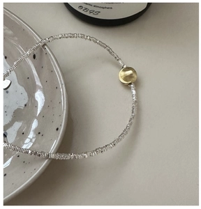 Detail of silver textured link chain with a matte gold bead in a minimalist style
