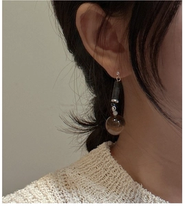 Detail of long drop earrings featuring deep brown beads on model with knit sweater