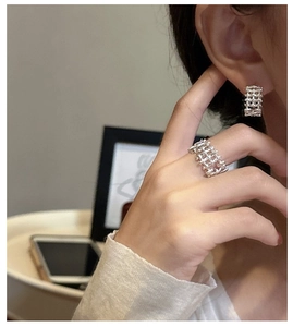 Macro detail of S925 sterling silver woven ring and earrings set on model