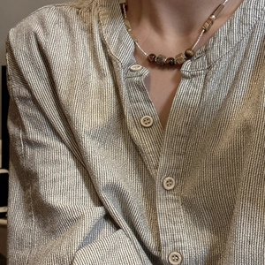 S925 silver beaded necklace with brown tiger eye stones worn over a striped shirt
