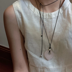 Collana con pendente a cuore in pietra naturale rosa con cordino nero su modella