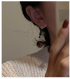 Detail of S925 silver earring with translucent brown beads on model in knitwear