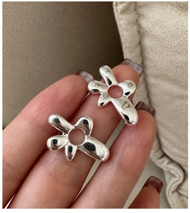 Macro shot of polished S925 sterling silver irregular flower earrings held by hand