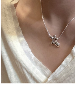 Macro shot of silver irregular cross star pendant necklace on model collarbone