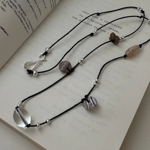 S925 silver beaded knot sweater necklace with crystal charms on a vintage book background