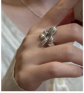 Gros plan d'une bague fleur fluide en argent poli portée sur le doigt d'un mannequin