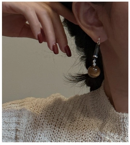 Close-up of a vintage S925 silver earring with a tiger eye stone bead on a model