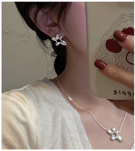 Detail view of S925 sterling silver floral earrings and matching necklace set on model
