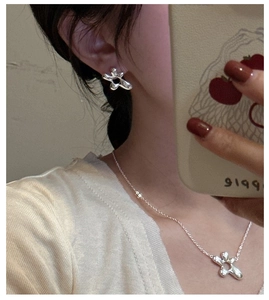 Close-up of S925 sterling silver irregular flower earrings and matching pendant necklace
