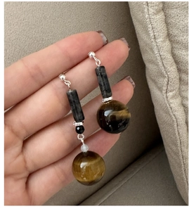 Detail of S925 silver earrings with tiger eye beads and cylinder stones in retro style