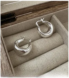 Macro shot of silver S925 U-shaped hoop earrings on vintage burlap jewelry box liner