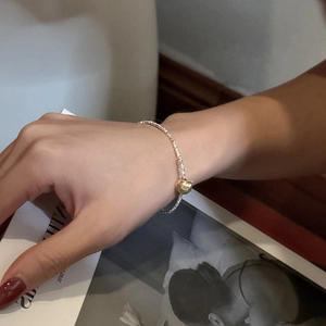 Minimalist S925 sterling silver bangle with gold bead detail on a textured band