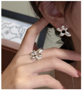 Detail view of silver abstract floral ring and earring set with black accent on model