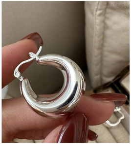 Macro shot of polished S925 sterling silver hoop earrings held by hand for detail