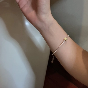 Minimalist S925 sterling silver bracelet with a golden bead worn on a woman's wrist
