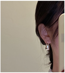 Close-up of chunky silver hollow hoop earrings with high-polish mirror finish surface