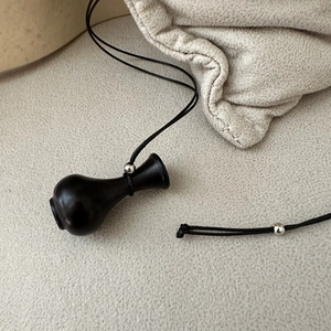 Collana vintage bottiglia in argento S925 con pendente in ebano nero su superficie grigia