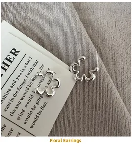 Dettaglio orecchini a fiore cavo in argento sterling S925 su sfondo estetico minimalista