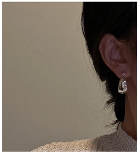 Close-up of a high-polished S925 silver irregular drop earring worn by a model