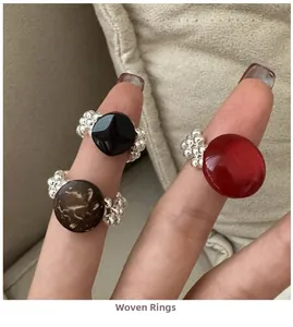 Detailed view of handmade woven rings with black, red and marble resin beads on a finger